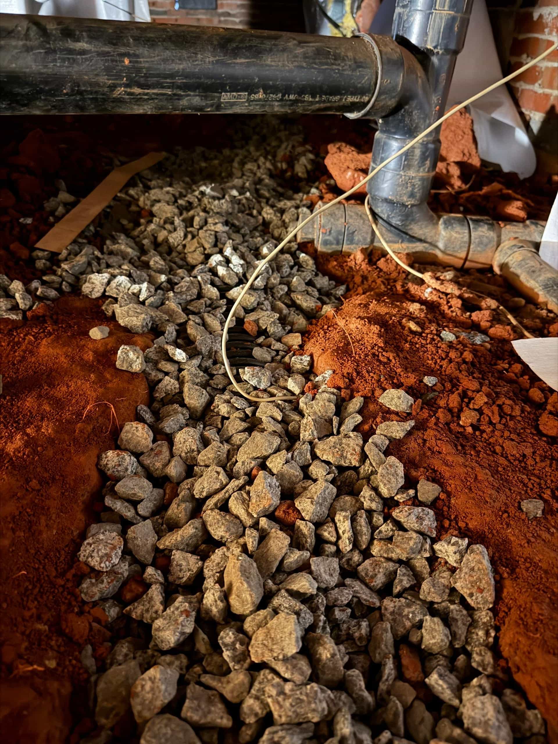 HydroHelp911 Crawl Space & Foundation Repair installing a crawl space drainage system with gravel and perforated pipe.