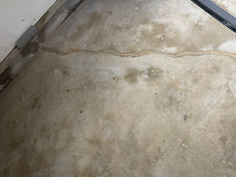 A crack running across a concrete garage floor near the garage door