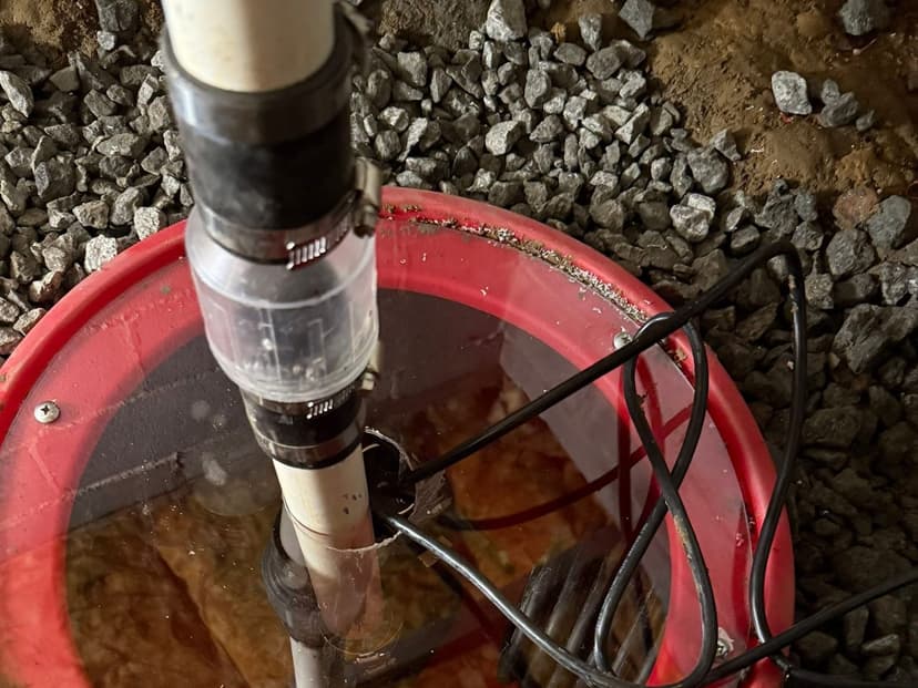 A sump basin set in gravel, with its discharge pipe and check valve
