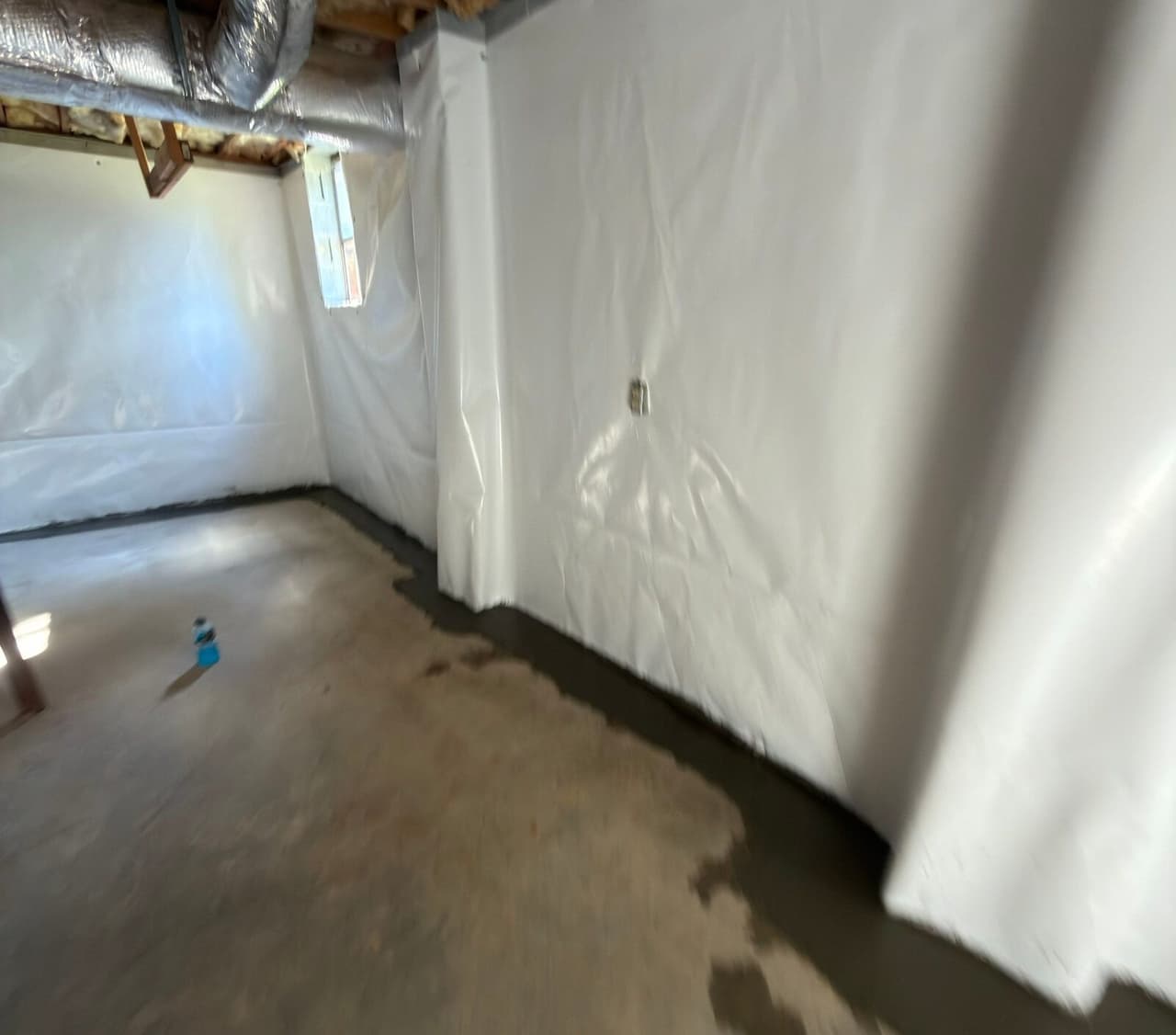 Basement walls in white liner with a fresh concrete strip along the floor edge.