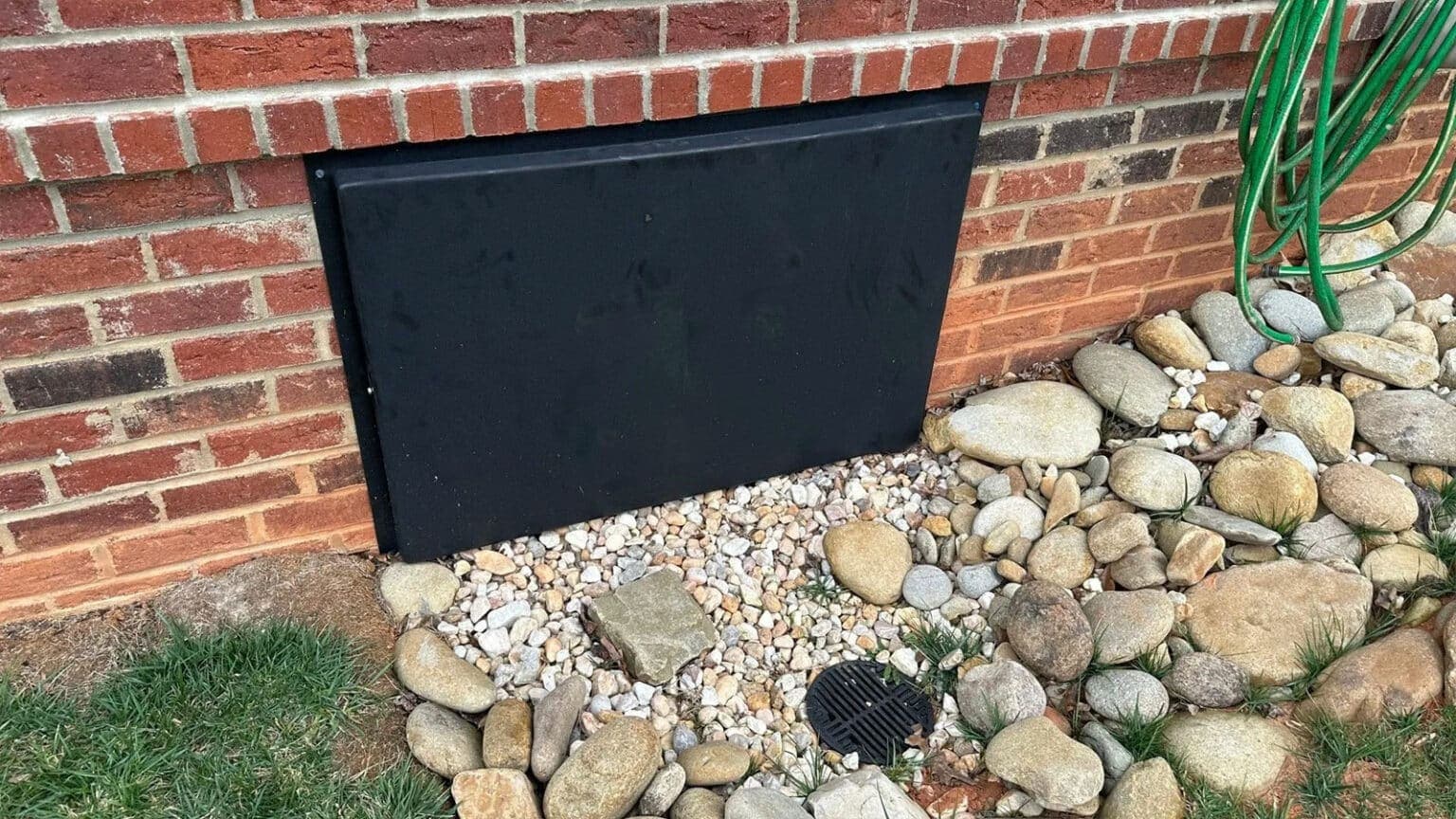 HydroHelp911 Crawl Space & Foundation Repair installing a new black crawl space access door in a brick foundation.