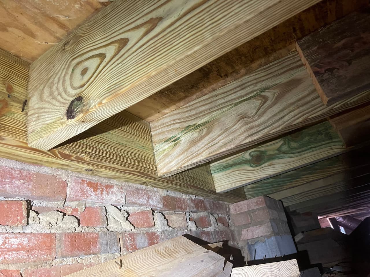 HydroHelp911 Crawl Space & Foundation Repair stabilizing new floor joists in a crawl space with damaged brick piers.