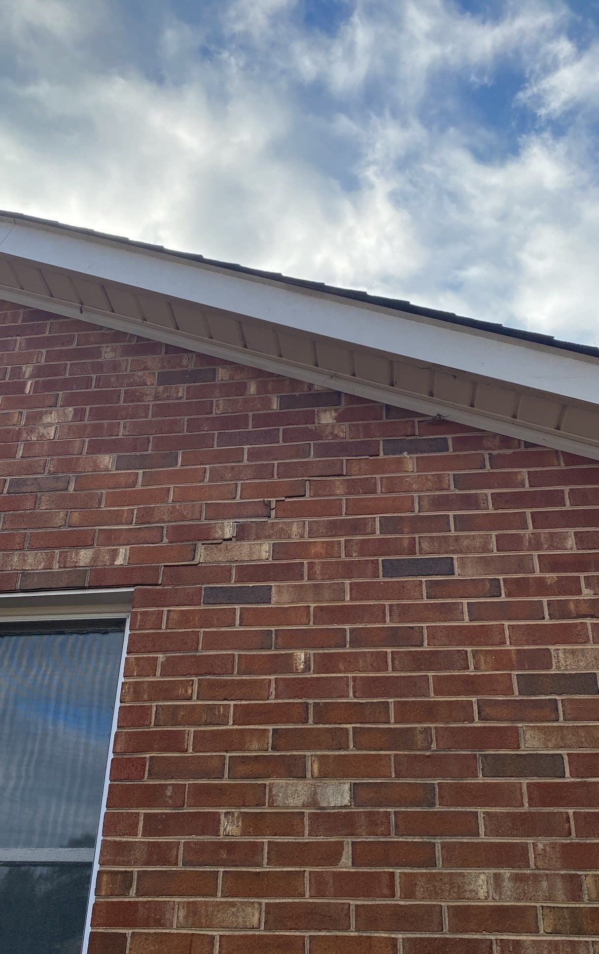 HydroHelp911 Crawl Space & Foundation Repair inspecting a stair step crack in exterior brick foundation.