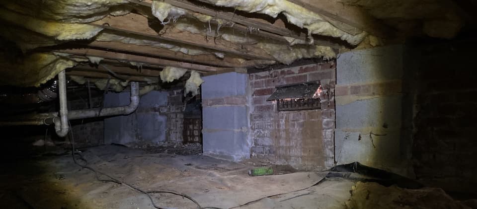 HydroHelp911 Crawl Space & Foundation Repair inspecting damp crawl space with deteriorated insulation and moisture.