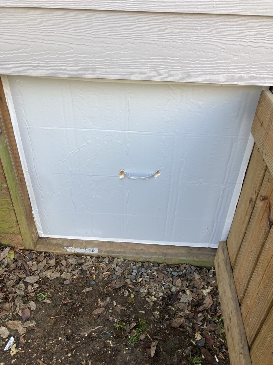 HydroHelp911 Crawl Space & Foundation Repair installing a new insulated crawl space access door on a home exterior.