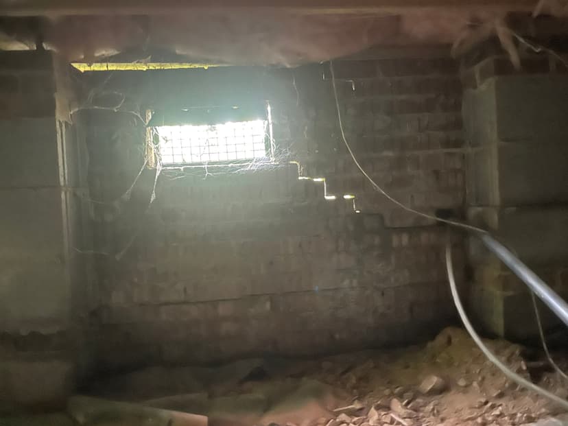 HydroHelp911 Crawl Space & Foundation Repair inspecting a stair step crack in a brick crawl space foundation.