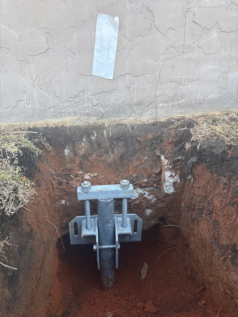 HydroHelp911 Crawl Space & Foundation Repair installing a steel pier for foundation underpinning with a bracket.