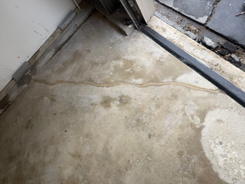 HydroHelp911 Crawl Space & Foundation Repair inspecting a cracked concrete garage floor for settlement signs.