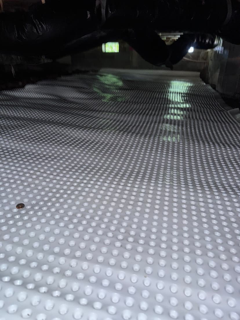 HydroHelp911 Crawl Space & Foundation Repair installing drainage matting, a dimpled membrane, in a crawl space.