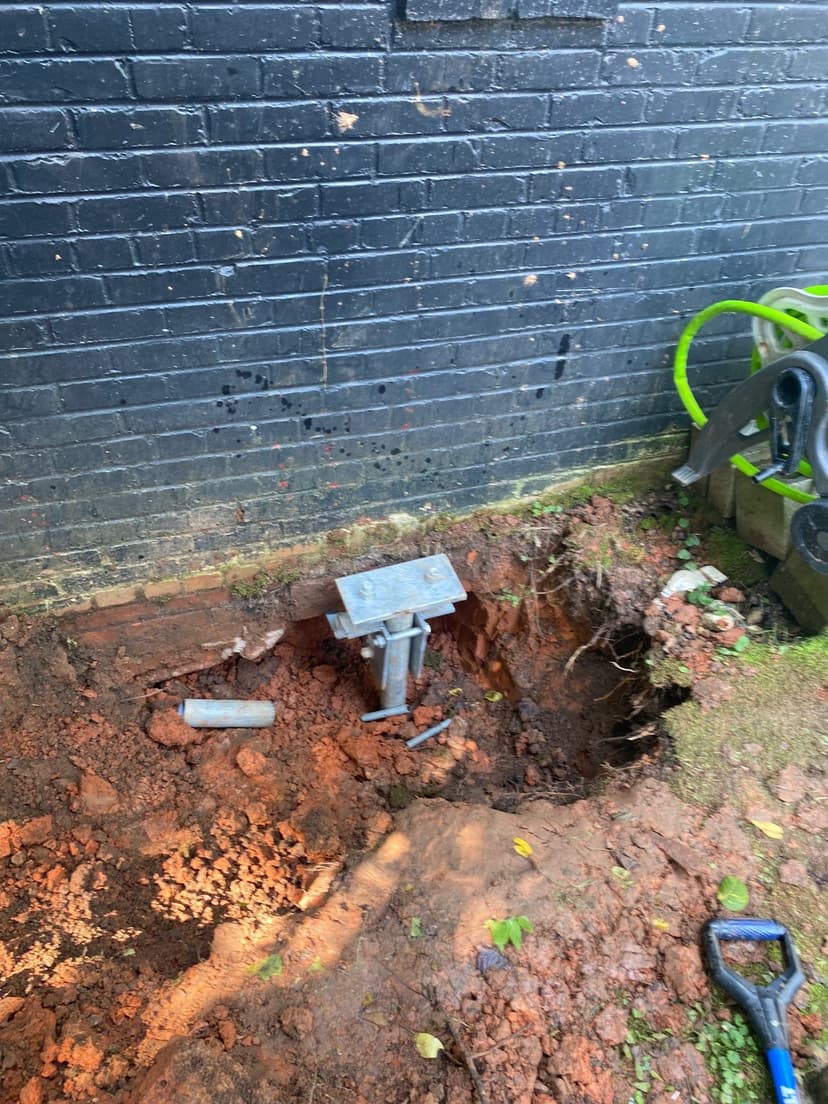 HydroHelp911 Crawl Space & Foundation Repair installing steel piers with a footing bracket for foundation underpinning.