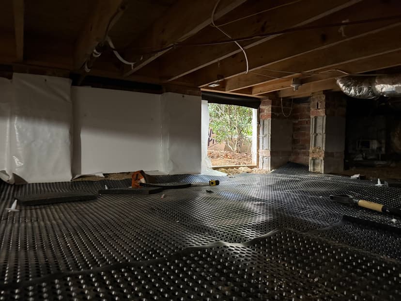 HydroHelp911 Crawl Space & Foundation Repair installing drainage matting and a vapor barrier in a crawl space