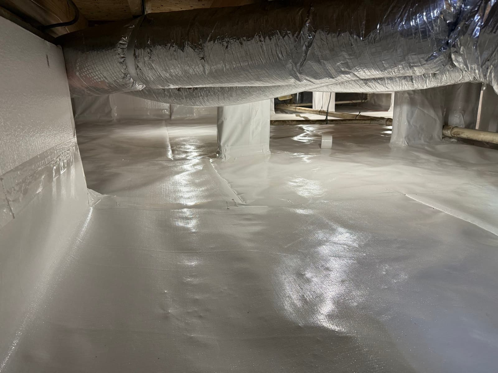 HydroHelp911 Crawl Space & Foundation Repair completed crawl space encapsulation with a white vapor barrier and sealed seams.