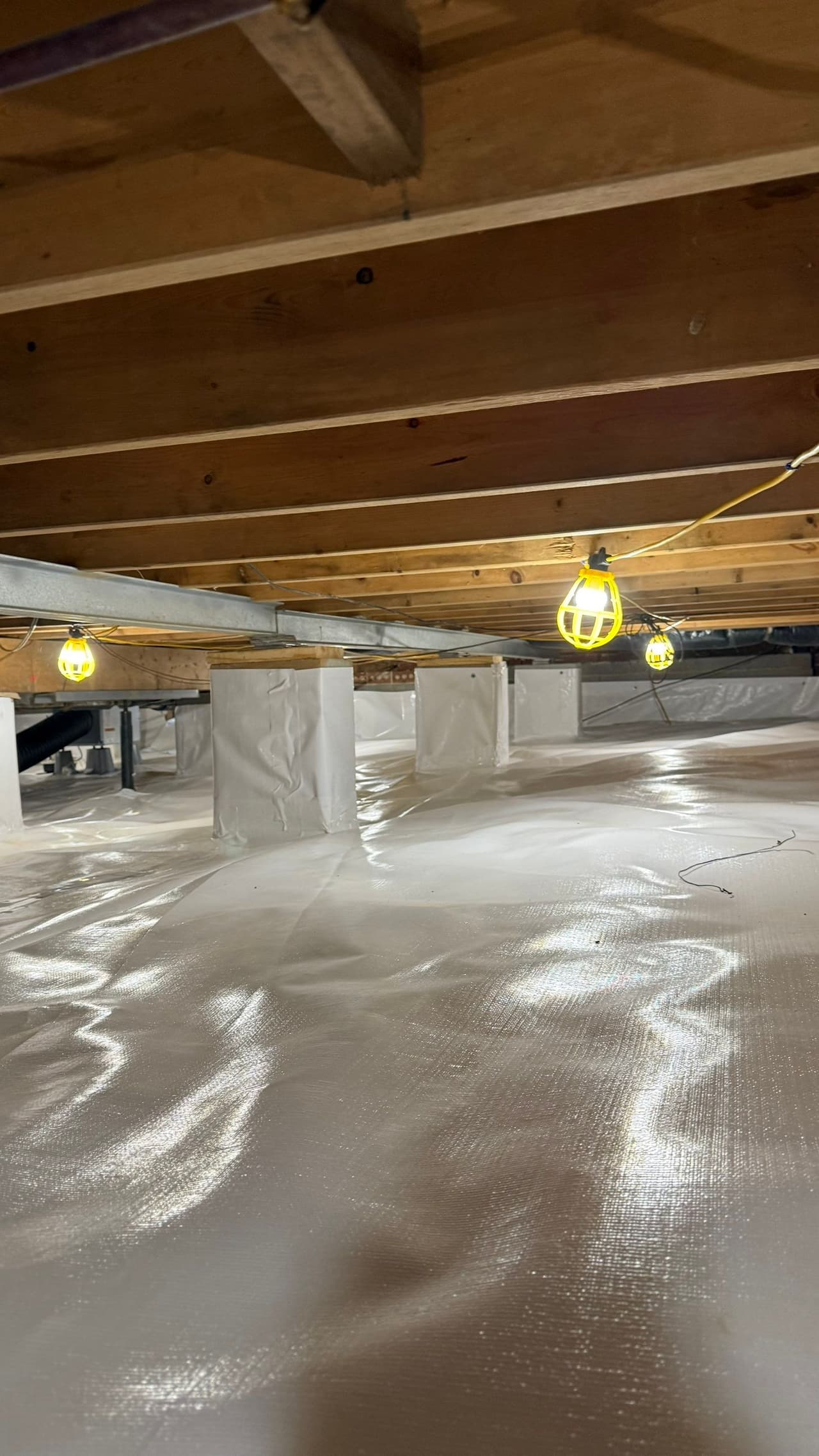 HydroHelp911 Crawl Space & Foundation Repair installing a white vapor barrier liner for crawl space encapsulation.