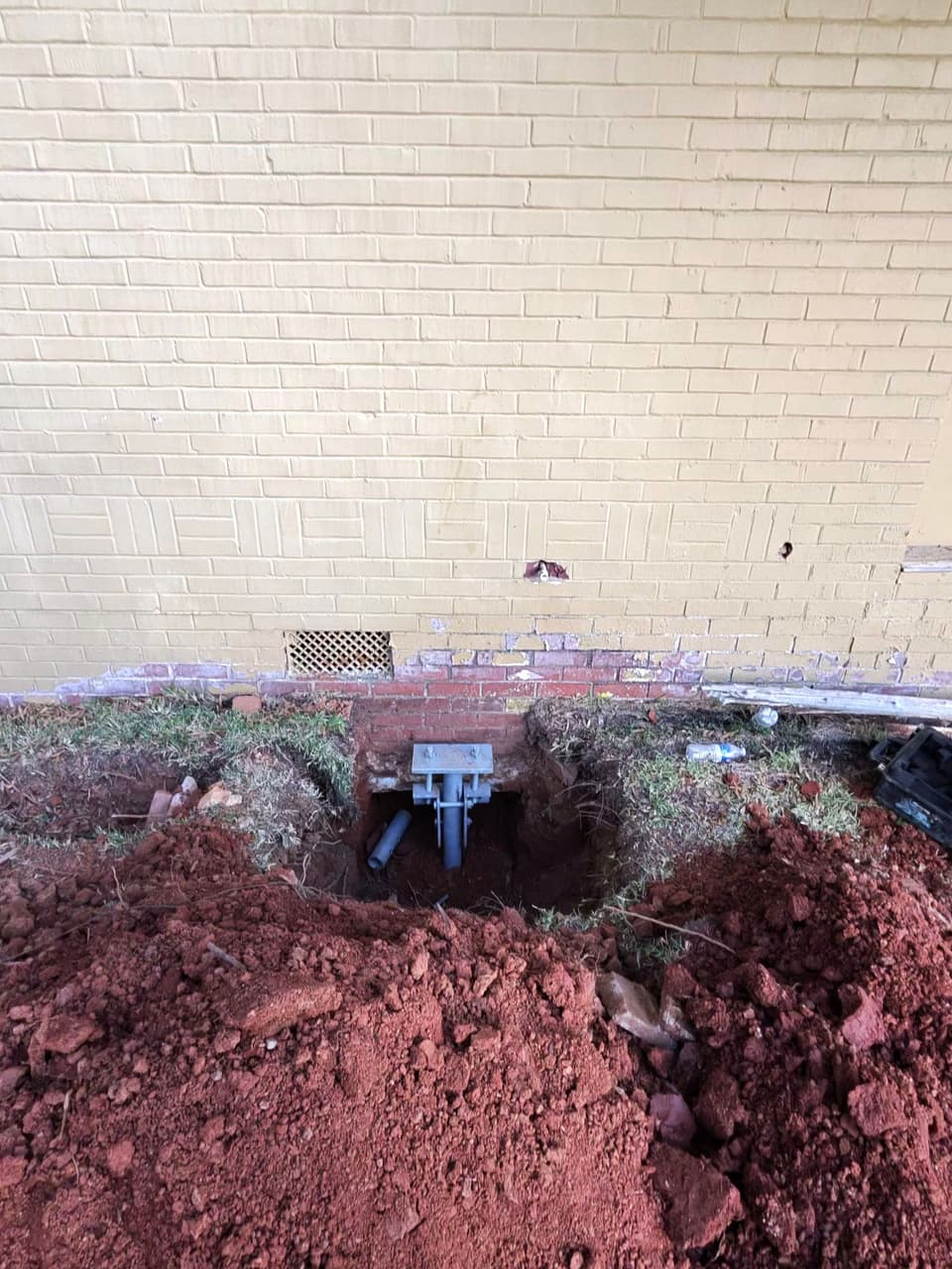 HydroHelp911 Crawl Space & Foundation Repair installing steel piers with a footing bracket for foundation underpinning.
