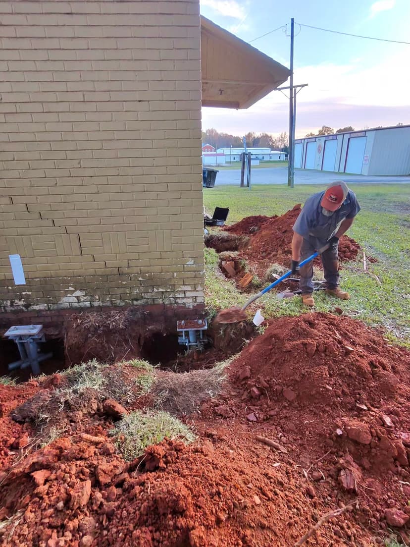 HydroHelp911 Crawl Space & Foundation Repair crew installing steel piers to stabilize a foundation with stair step cracks.