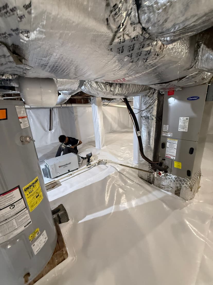 HydroHelp911 Crawl Space & Foundation Repair technician installing a vapor barrier and dehumidifier in a crawl space.