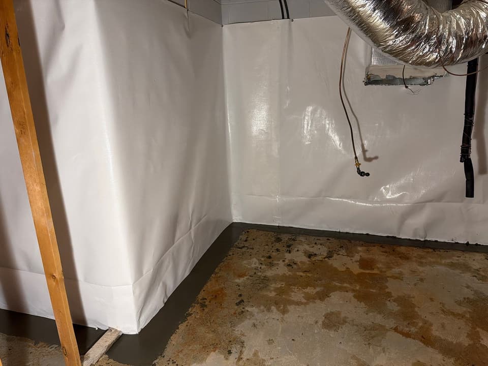 HydroHelp911 Crawl Space & Foundation Repair installing a white vapor barrier and interior drainage system in a basement.