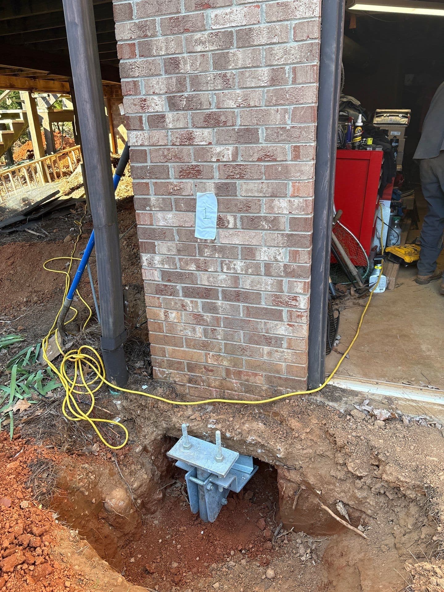 HydroHelp911 Crawl Space & Foundation Repair installing steel piers for foundation underpinning with a footing bracket.