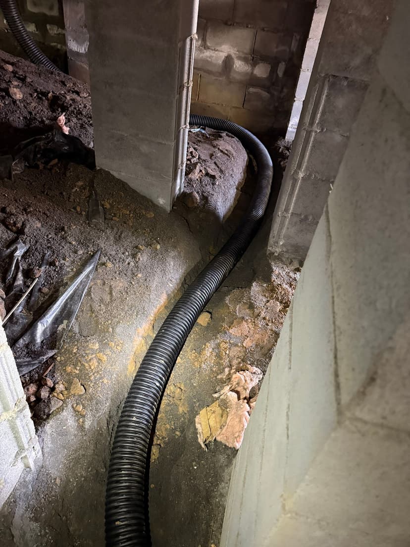 HydroHelp911 Crawl Space & Foundation Repair installing a perforated drainage pipe in a crawl space drainage trench.