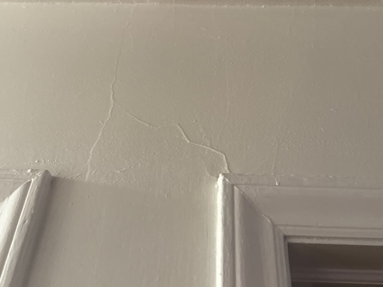 HydroHelp911 Crawl Space & Foundation Repair inspecting drywall cracks around an interior door frame