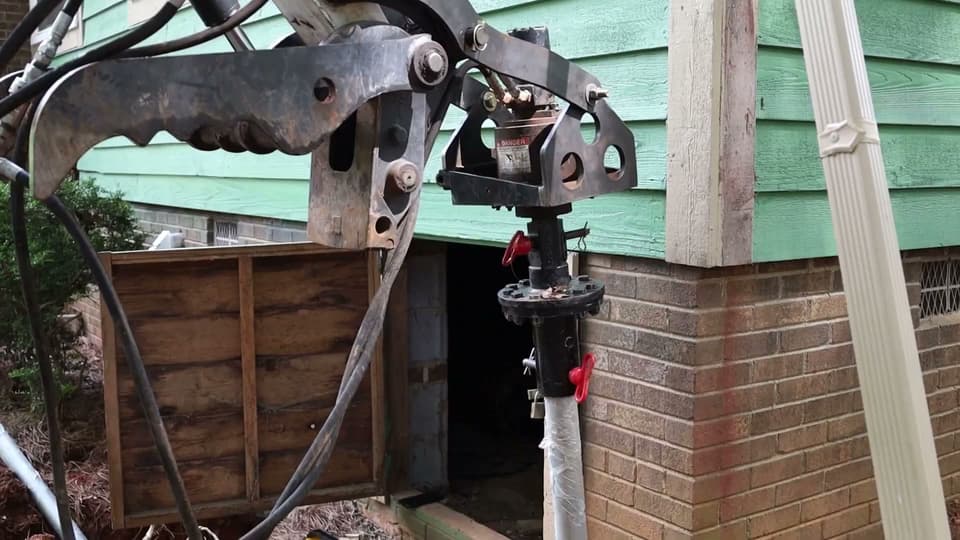 HydroHelp911 Crawl Space & Foundation Repair installing helical piers with a rotary drive head for foundation underpinning.