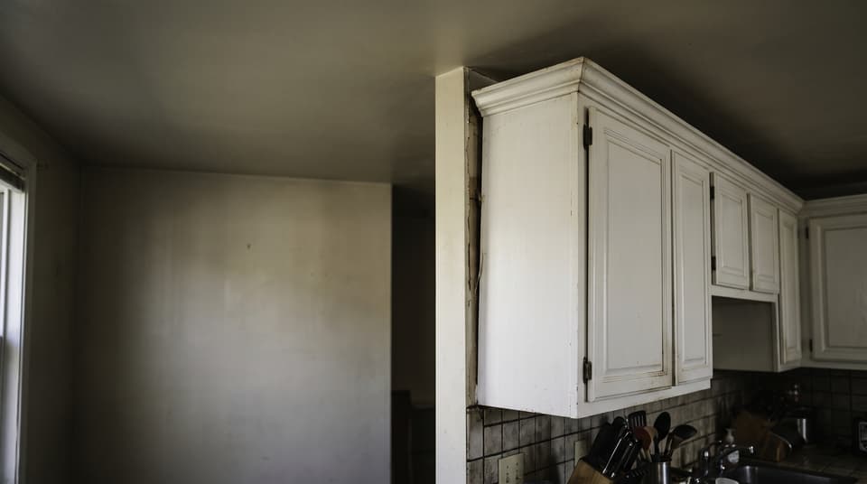 HydroHelp911 Crawl Space & Foundation Repair inspecting a kitchen wall with detached cabinets