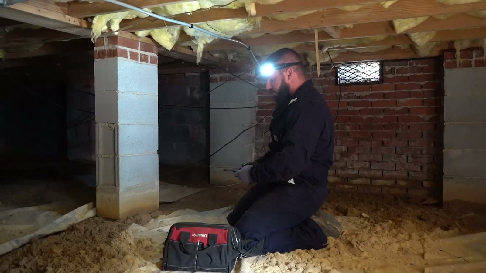 HydroHelp911 Crawl Space & Foundation Repair technician inspecting a crawl space with deteriorating insulation.