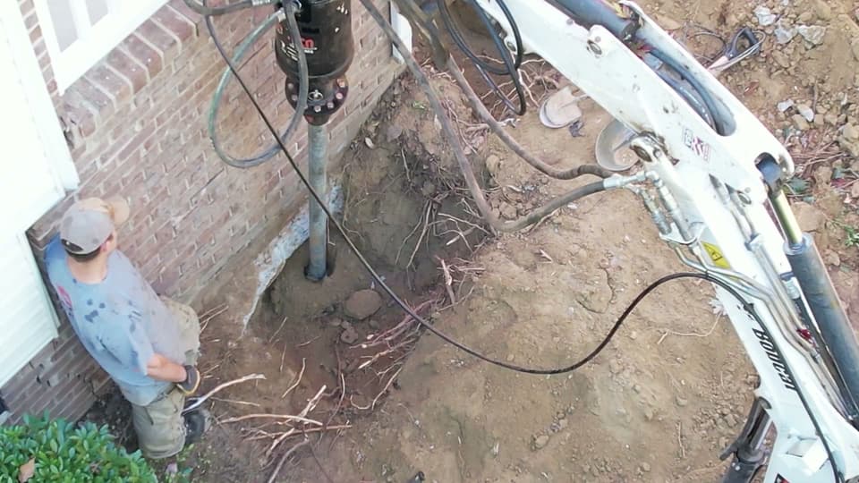 HydroHelp911 Crawl Space & Foundation Repair installing steel helical piers for foundation underpinning