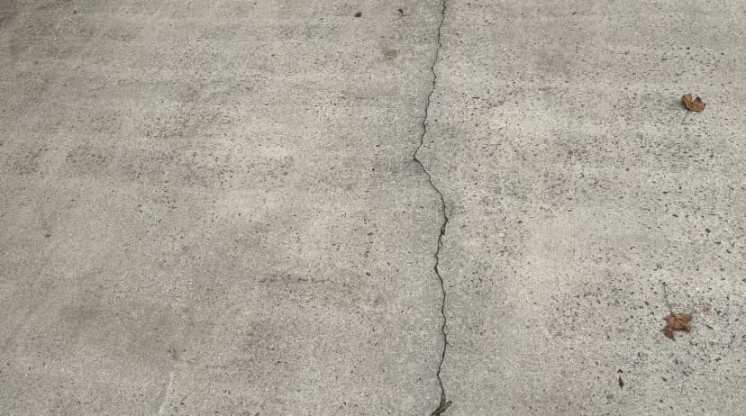 A crack running across a concrete driveway slab