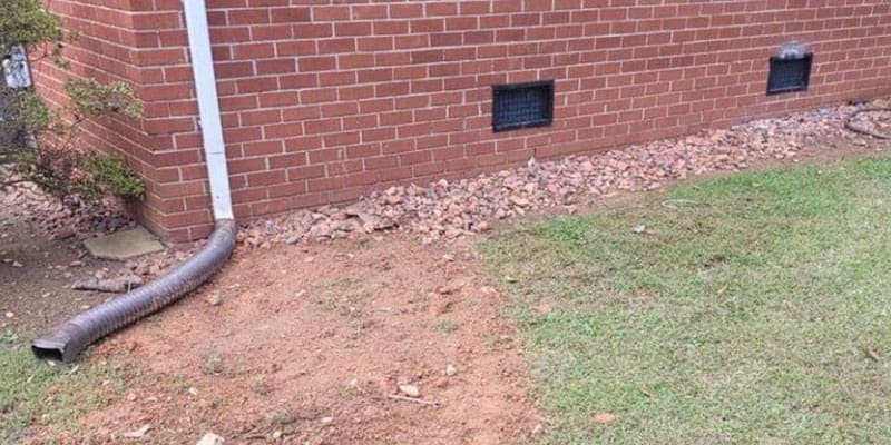 Downspout with a flexible extension beside a brick house