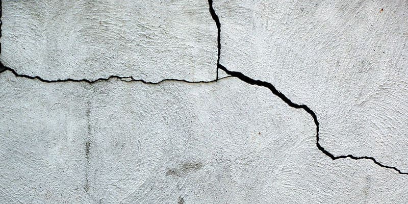 Stair step crack running across a stucco foundation wall