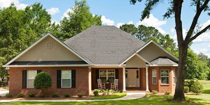 Brick ranch house with a front lawn and large trees
