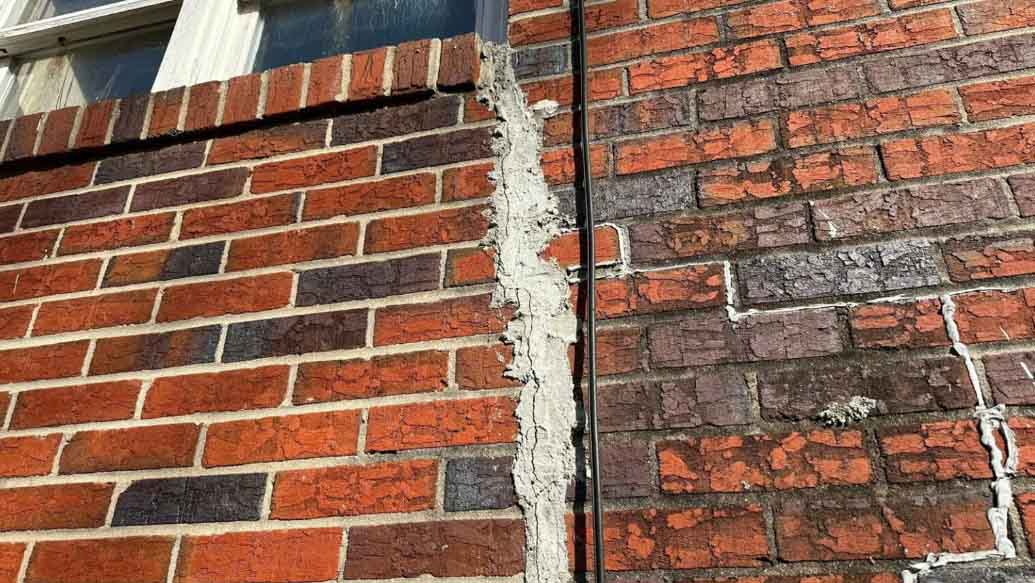 Vertical crack running through mortar joints in a brick wall