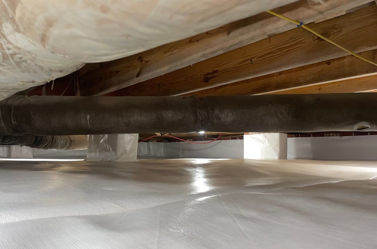 Duct running across a crawl space with liner on the floor, walls and wrapped piers.
