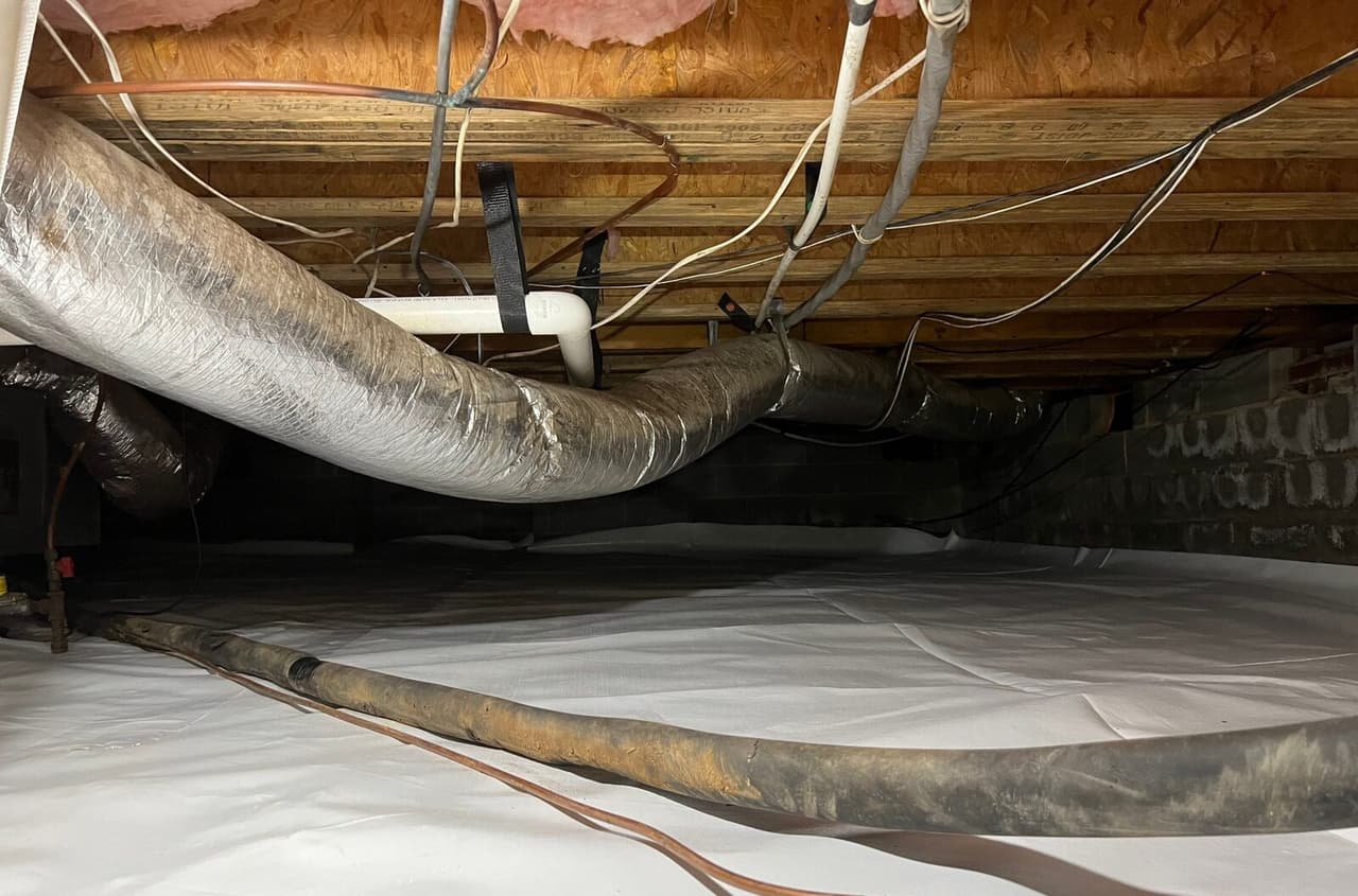 White crawl space liner covering the floor under the ductwork.