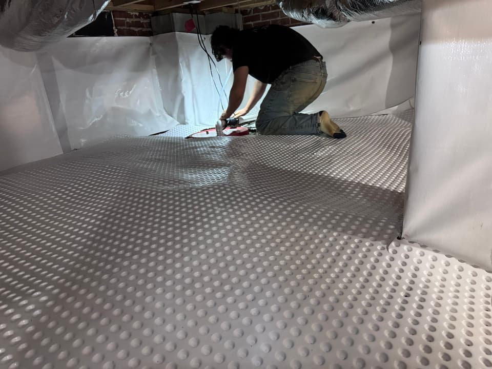 HydroHelp911 Crawl Space & Foundation Repair crew installing a crawl space drainage matting and vapor barrier.