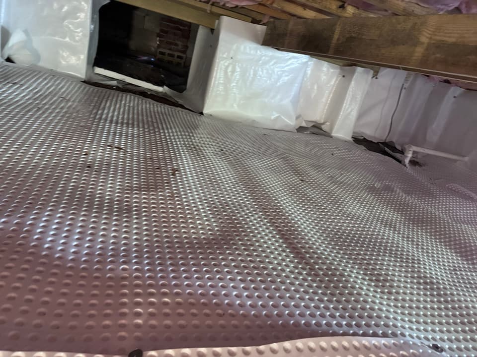 HydroHelp911 Crawl Space & Foundation Repair installing dimpled drainage matting and a vapor barrier in a crawl space.