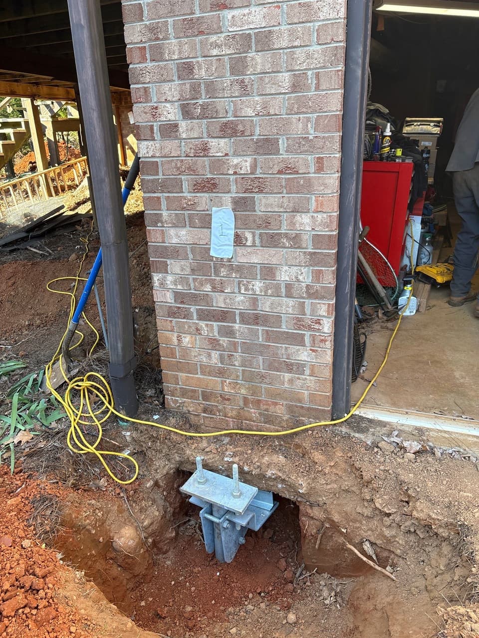 HydroHelp911 Crawl Space & Foundation Repair installing steel piers for foundation underpinning with a footing bracket.