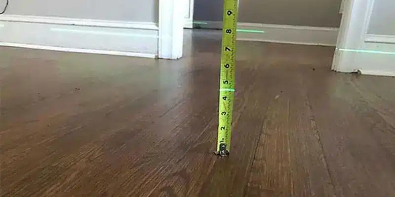Tape measure checking a dip in a wood floor